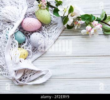 String bag with Easter eggs and spring blossom in corner of a rustic wooden table Stock Photo