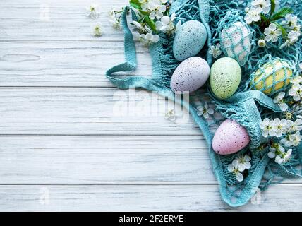 String bag with Easter eggs and spring blossom in corner of a rustic wooden table Stock Photo