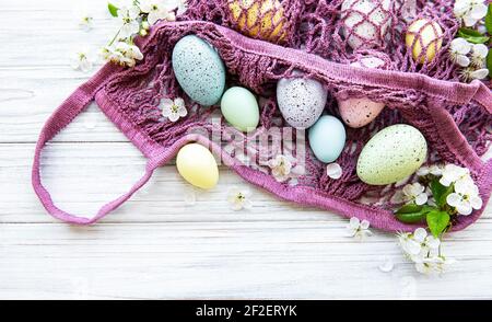 String bag with Easter eggs and spring blossom in corner of a rustic wooden table Stock Photo