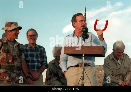 President George H. W. Bush holds up a horseshoe as he addresses the Marines and Seabees at a desert encampment. Stock Photo