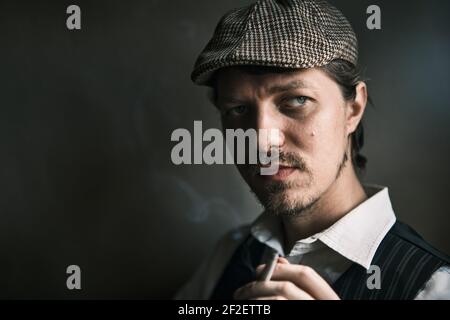 Young guy smoke cigarette, blows smoke, dressed in a retro style, in a beret, cinematic shot, big closeup Stock Photo