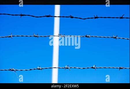 three lines of barbed wire against a blue background Stock Photo