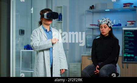Professional researcher wearing virtual reality glasses using medical inovation in lab analysing brain scan of patient. Team of neurological doctors working with equipment high tech simulator device Stock Photo