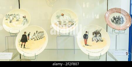 Several ceramic plates with painted army motives. Pictures of historic soldiers. Exhibits in Museum of ceramics, Sarreguemines, Moselle, France. Stock Photo