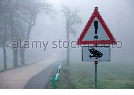 A red warning sign for drivers on a country road in Germany as frogs enter mating season. Common frogs awake from hibernation in Spring. Stock Photo