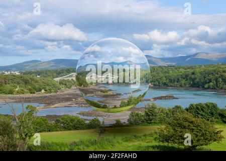 Menai suspension bridge build by Thomas Telford over the Menai Strait in North Wales UK seen through a floating glass crystal ball. Stock Photo