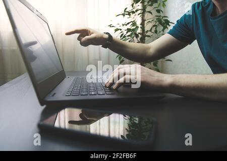 Male person use laptop at his home. Side view shot of man working and typing on keyboard at his home or office Stock Photo