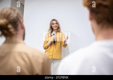 Blonde coach with a microphone talking to the audience Stock Photo