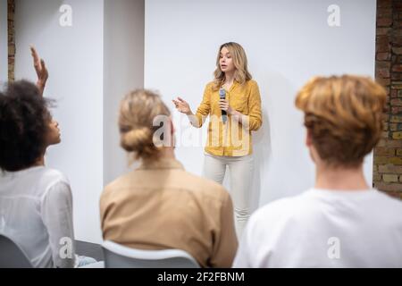 Blonde coach with a microphone talking to the audience Stock Photo
