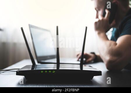 Internet WIFI router and man in background working on computer and talking with phone Stock Photo