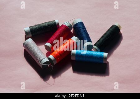 Multicolor sewing threads on pink background