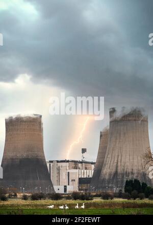 Flash bolt of lightning striking electric power station with cooling tower steam chimneys in storm with dramatic stormy clouds overhead and wildlife Stock Photo