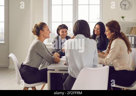 Group of young businesswomen meeting around office table and discussing new ideas Stock Photo