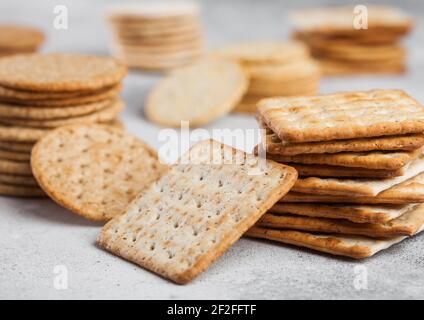 Stack of various organic crispy wheat, rye and corn flatbread crackers with sesame and salt on light background Stock Photo