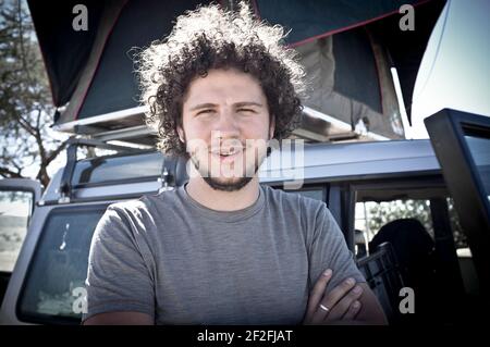 Young man stands in front of vehicle, half portrait Stock Photo