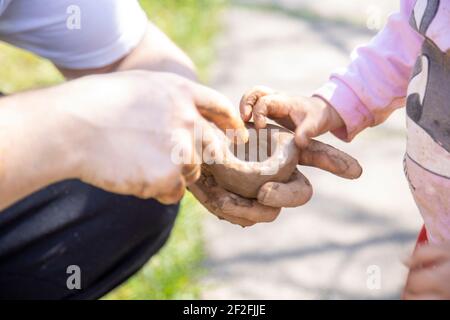 dad and toddler make clay outside on a sunny day close-up. no face Stock Photo