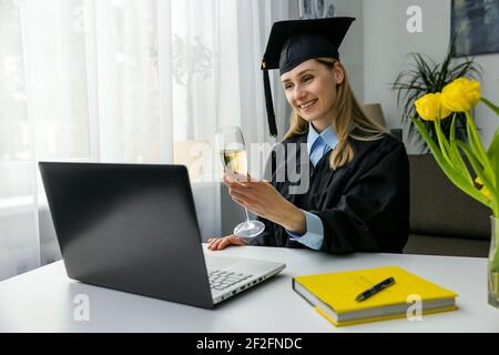 online graduation celebration - happy woman using laptop and drinking champagne together with university friends Stock Photo