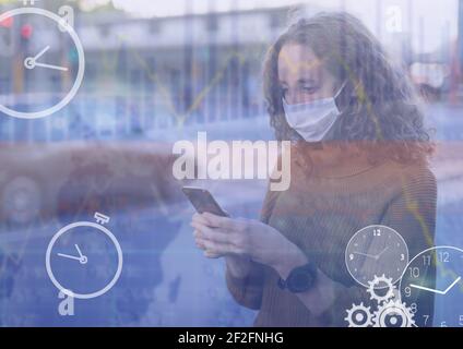 Digital clocks and financial data processing against woman wearing face mask using smartphone Stock Photo