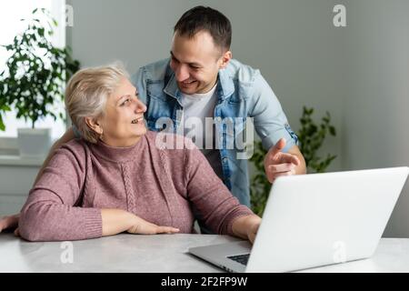Portrait of a senior woman and a man in front of a laptop computer Stock Photo