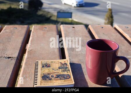 Coffee Mug and Small Notebook on Wooden Desk Outdoor Stock Photo