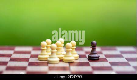 Discrimination concept. A group of white chess figures exclude a single brown chess figure. Stock Photo