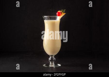 Pina colada cocktail decorated with a piece of pineapple and cherry on black background Stock Photo