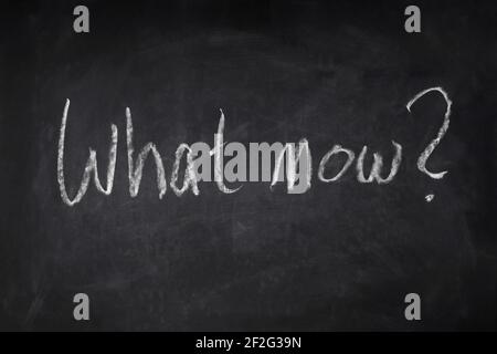 what now handwritten question on chalkboard - uncertainty, angst Stock Photo