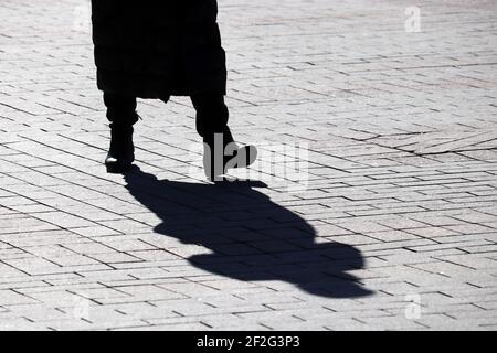 Black silhouette and long shadow of lonely slim girl walking on a ...