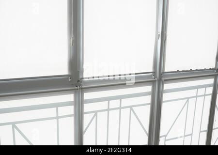 White fabric roller blinds on the plastic window on a balcony in the living room. Stock Photo