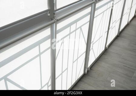 White fabric roller blinds on the plastic window on a balcony in the living room. Stock Photo