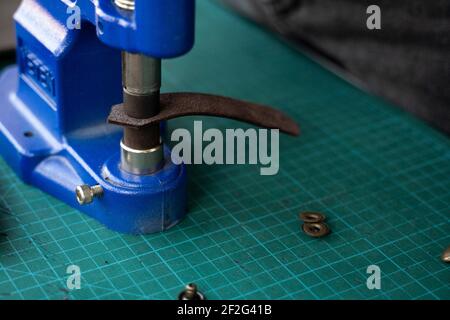 Artisan using hand press for setting snaps in leather for makes a wallet. Hand Pressure Snap Pressing Machine is using by craftsman in leather Stock Photo
