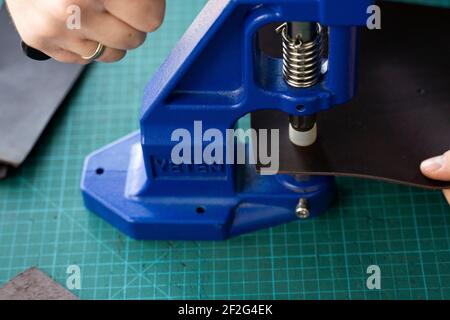 Artisan using hand press for setting snaps in leather for makes a wallet. Hand Pressure Snap Pressing Machine is using by craftsman in leather Stock Photo