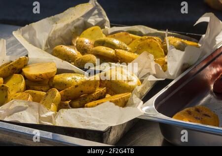Street food in Ukraine - grilled  potatoes lying on a metal tray tray in parchment paper and ready to be served Stock Photo