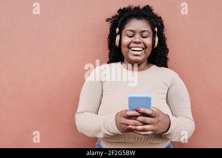 Young african woman listening music with headphones outdoors in the city - Focus on face Stock Photo