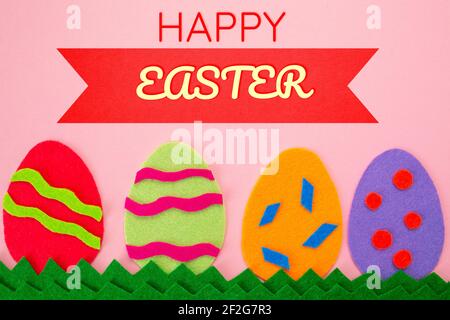 Easter. Cut out the felt applications of four colorful eggs on pink background. Flat lay. Stock Photo