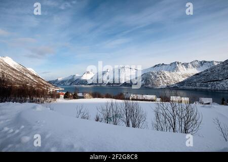 Scenery of snow mountain range and norwegian village on coastline in winter at Senja Island, Norway Stock Photo