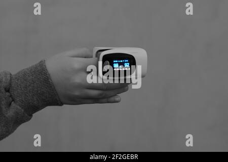 fingertip pulse oximeter equipment connected to the index finger of a child measuring oxygen saturation in blood and heart rate Stock Photo