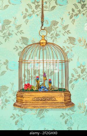 Vintage hanging birdcage with old figurine birds in front of wallpaper with flower pattern Stock Photo