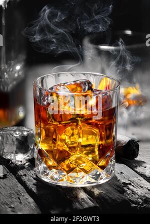 Cigar and glass with whiskey with ice cubes Stock Photo