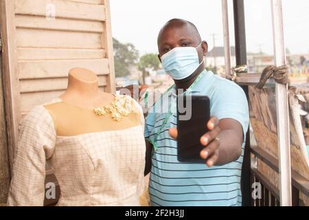 an african tailor holding his phone Stock Photo