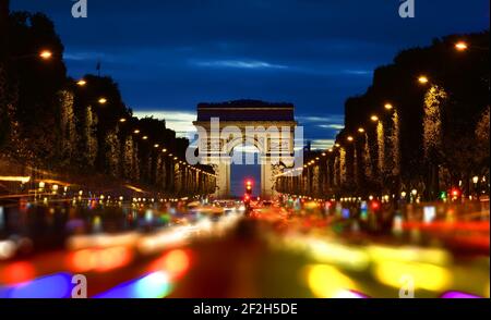 Evening rush-hour on Champs Elysee with the view of illuminated Arc de Triomphe in Paris, France Stock Photo