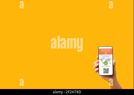 Woman's hand holding smartphone displaying valid digital vaccination certificate and QR code on isolated background. Digital vaccination passport for COVID19 for for all people who travel.Copy space. Stock Photo