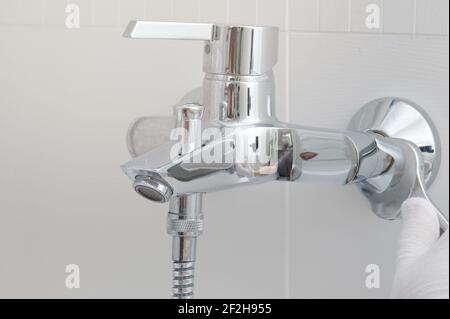 Installing new faucet in bathroom close up view. Plumber hand with wrench Stock Photo