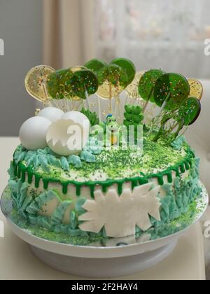 There is a beautiful birthday cake in green tones on a creamy table. Preparing for a child's birthday party. Celebrating a joyful event Stock Photo