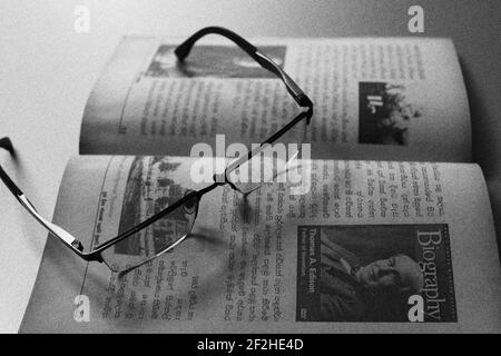 The reader is tired, he has kept his spectacles on the book. Stock Photo
