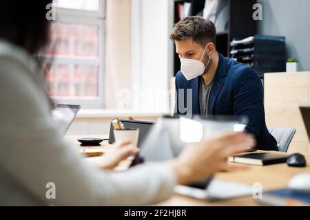 Man Employee In Office Wearing Face Mask Working On Computer Stock Photo