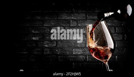 Wine pouring in wineglass near brick wall Stock Photo