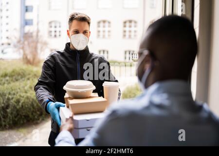Receiving Pizza From Delivery Man In Face Mask At Home Stock Photo