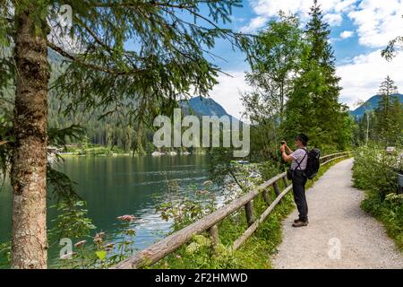 Man films the landscape, Hintersee, Ramsau, in the back Reiteralpe, Berchtesgaden, Berchtesgaden Alps, Berchtesgaden National Park, Berchtesgadener Land, Upper Bavaria, Bavaria, Germany, Europe Stock Photo