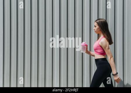 Sports and Hydration, Drink water, Stay Hydrated During Exercise. Fitness young woman, teen girl drinking water after outdoor running workout in sun Stock Photo